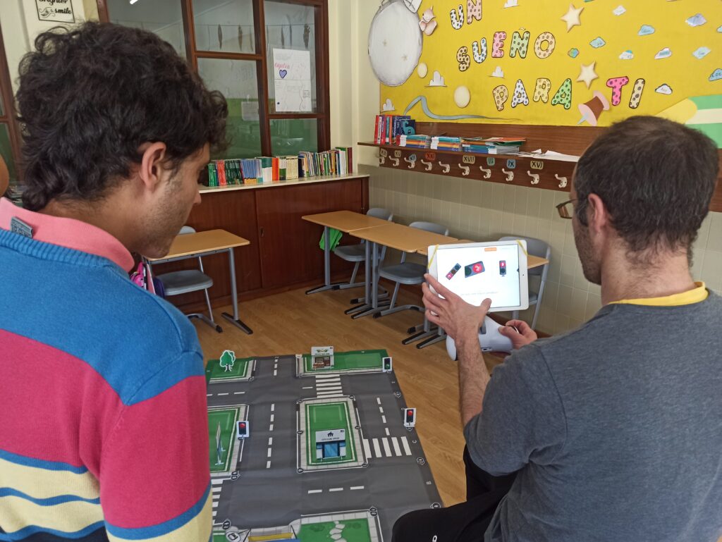 Docentes programando en una tablet al robot Photon para que pueda identificar semáforos